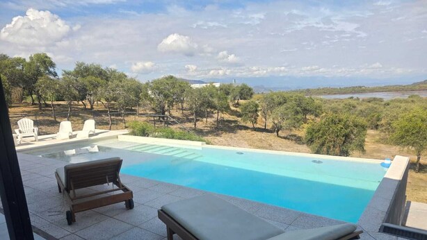 A swimming pool with two sun loungers and a view of a natural landscape. - "PARADISE". (Coronel Moldes)