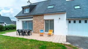 A modern house with a patio, a dining table with chairs, and two lounge chairs. - Ty Kroesi - La maison du port (Arzon)
