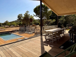 A pool area with a wooden deck, outdoor seating, and a view of the surrounding landscape.