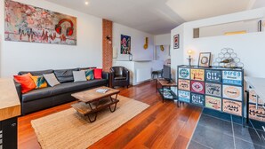 Una sala de estar moderna con un sofá de cuero negro, una mesa de centro de madera y una pared de ladrillo decorativa.