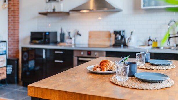 Una cocina con encimera de madera, tostadora, cafetera y pared de ladrillo.