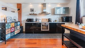 Una cocina moderna con armarios negros, encimera de madera y horno empotrado.