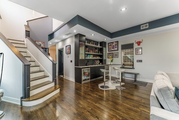 Une cuisine moderne avec un coin bar, une table à manger et un escalier.