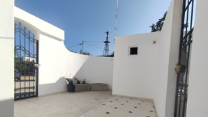 A courtyard with a tiled floor, a gate, and potted plants.