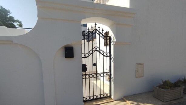A gated entrance with a metal gate and a small mailbox.