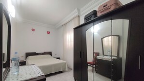 A hotel room with a bed, a dresser, a mirror, and a wardrobe.