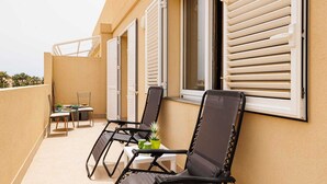 Un balcón con dos sillones negros, una mesita y una silla.