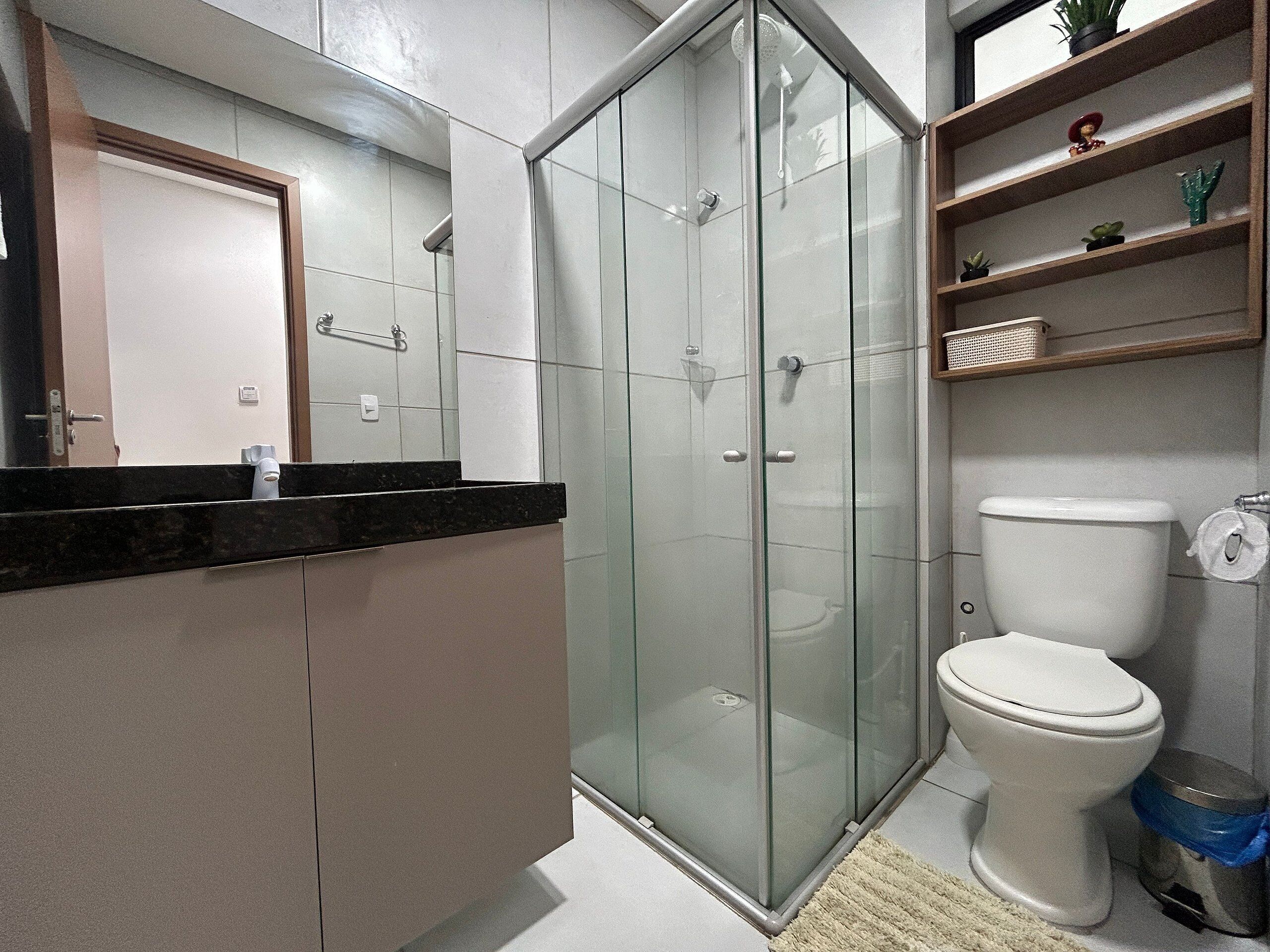 A modern bathroom with a glass shower enclosure, a toilet, and a vanity with a mirror.