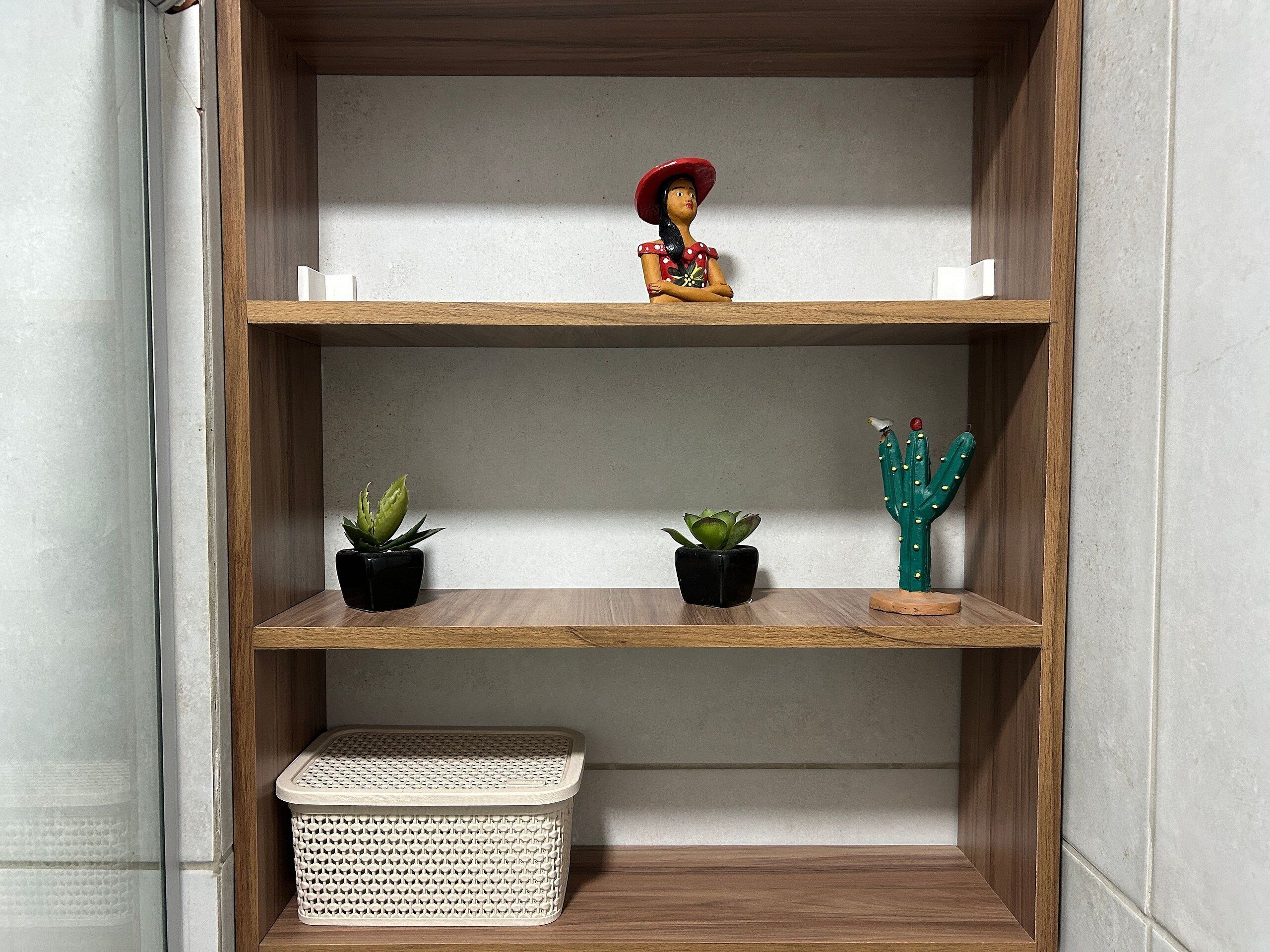 Un mueble de madera con tres estantes, cada uno con una planta en maceta y una figurita.