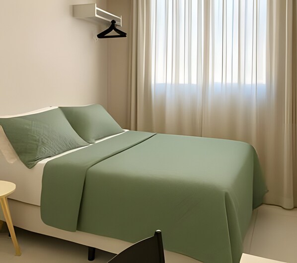 A neatly arranged bedroom with a bed, a chair, a small table, and a hanging light fixture.