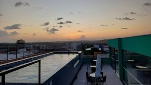 Ein Poolbereich auf dem Dach mit Blick auf den Sonnenuntergang und die ferne Landschaft.