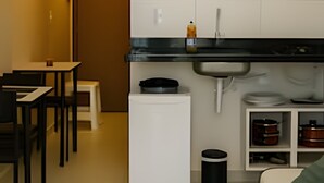 Eine kompakte Küche mit Mikrowelle, Spüle und kleinem Kühlschrank. Es gibt einen Essbereich mit Tisch und Stühlen.