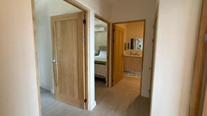 A hallway with wooden doors leading to a bedroom and a bathroom. - Oceanview Apt, 3BR/2BA in The Catalinas, 5 min walk to the beach, free parking (Las Catalinas)