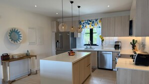 A modern kitchen with a central island, stainless steel appliances, and pendant lighting. - Oceanview Apt, 3BR/2BA in The Catalinas, 5 min walk to the beach, free parking (Las Catalinas)