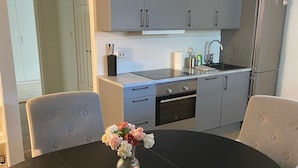 A modern kitchen with grey cabinets, a black countertop, and a dining table with a vase of flowers.