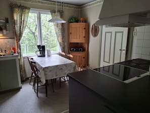 Una cocina con una mesa de comedor, sillas, cafetera, microondas y estufa.
