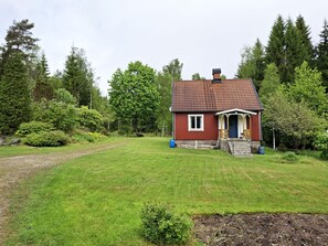 A small house with a red exterior, a chimney, and a porch.