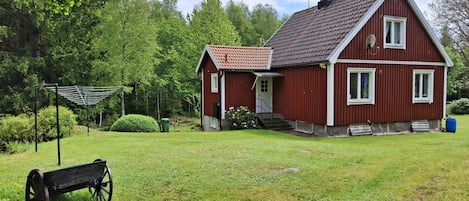 A red house with a sloped roof, a chimney, and a small porch.