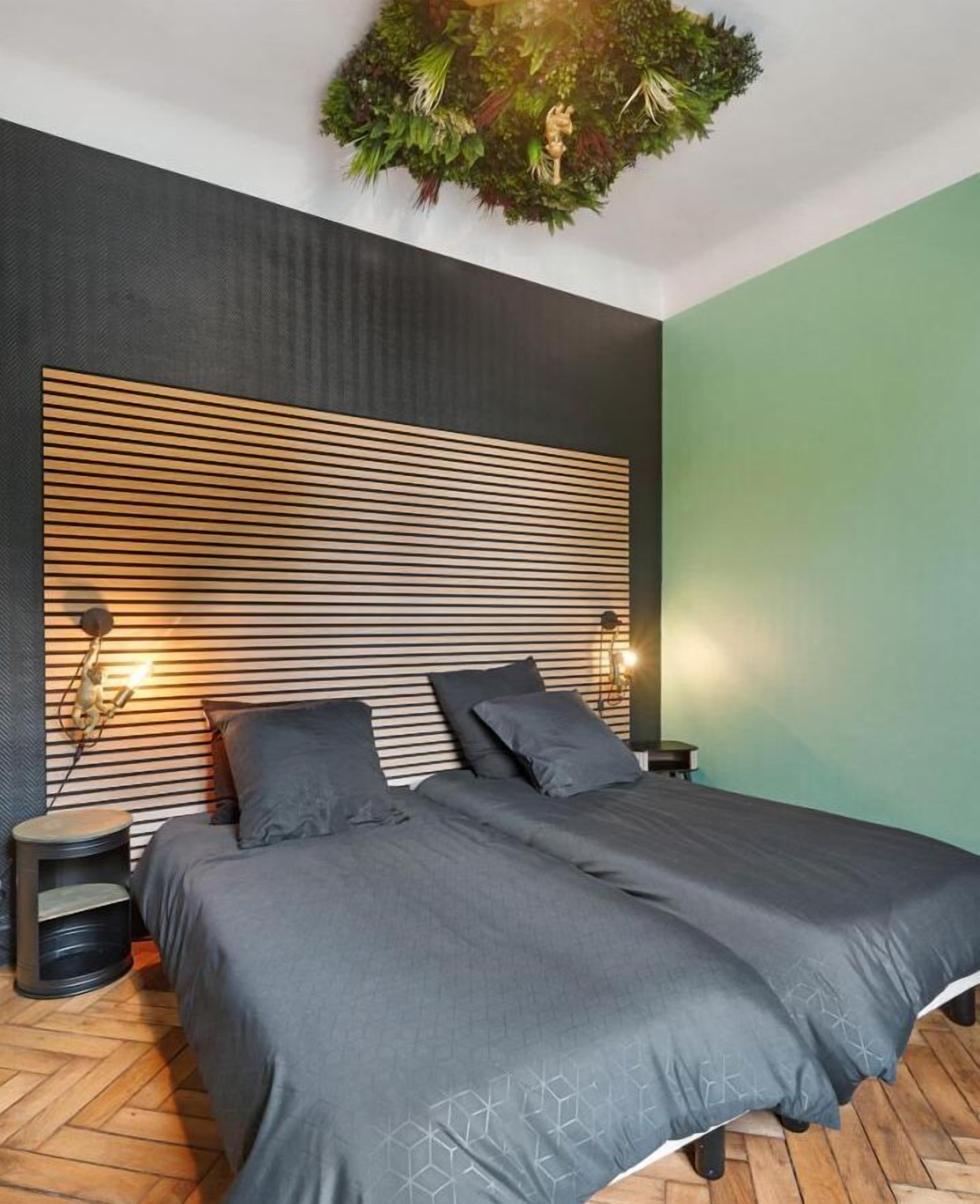 Une chambre moderne avec un grand lit, deux tables de chevet et un mur vert original.