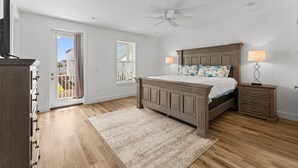 A bedroom with a wooden bed, two bedside tables with lamps, a ceiling fan, and a view through a door. - Cobian Pearl with LSV and Game Rooms (Miramar Beach)