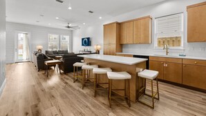 A modern kitchen with wooden cabinets, a white countertop, and bar stools. - Cobian Pearl with LSV and Game Rooms (Miramar Beach)