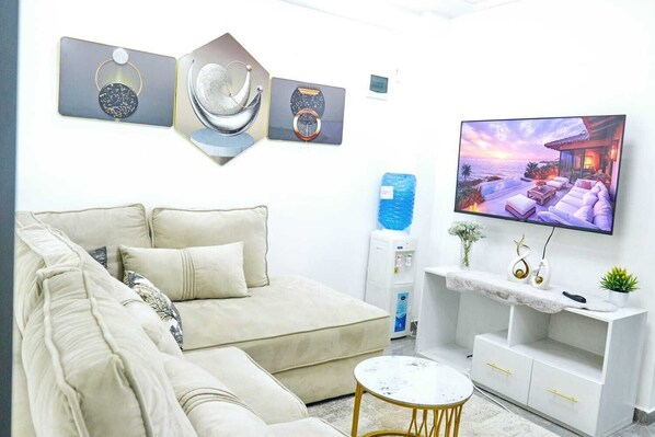 A modern living room with a beige sofa, a flat-screen TV, and decorative wall art.