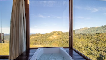 Una habitación con un ventanal grande, una bañera y vistas a un paisaje montañoso.