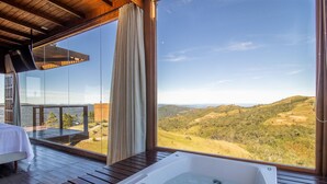 Una habitación con un ventanal grande, una terraza de madera y un jacuzzi.
