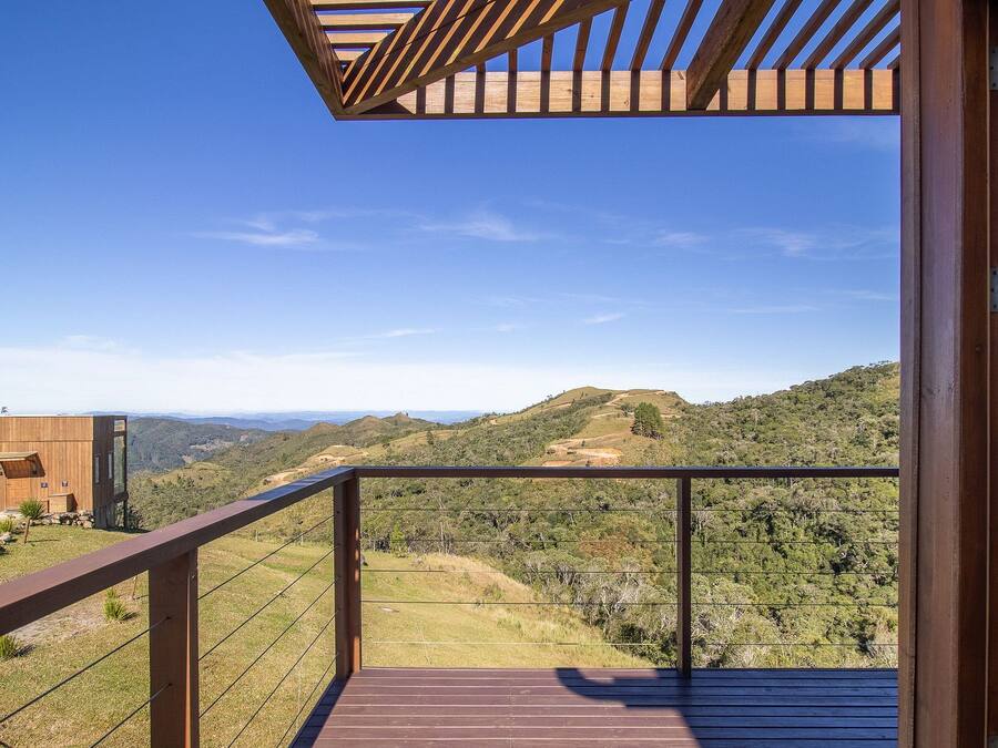 En træterrasse med gelænder i metal med udsigt over et bakket landskab.