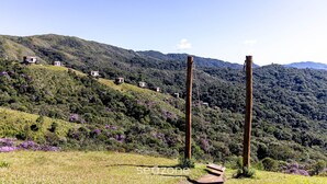 Una colina con varios edificios pequeños, una construcción de madera y un cielo despejado.