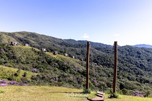 Une colline parsemée de plusieurs petits bâtiments, une structure en bois et un ciel dégagé.