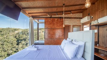 Un dormitorio con una cama grande, vistas al exterior y paredes de madera.