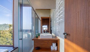 A modern bathroom with a large window, a wooden vanity, a sink, and a toilet.