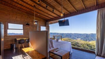 Una habitación con cama, escritorio, silla, televisión y vistas a las montañas.