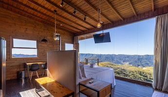 Una habitación con cama, escritorio, silla, televisión y vistas a las montañas.