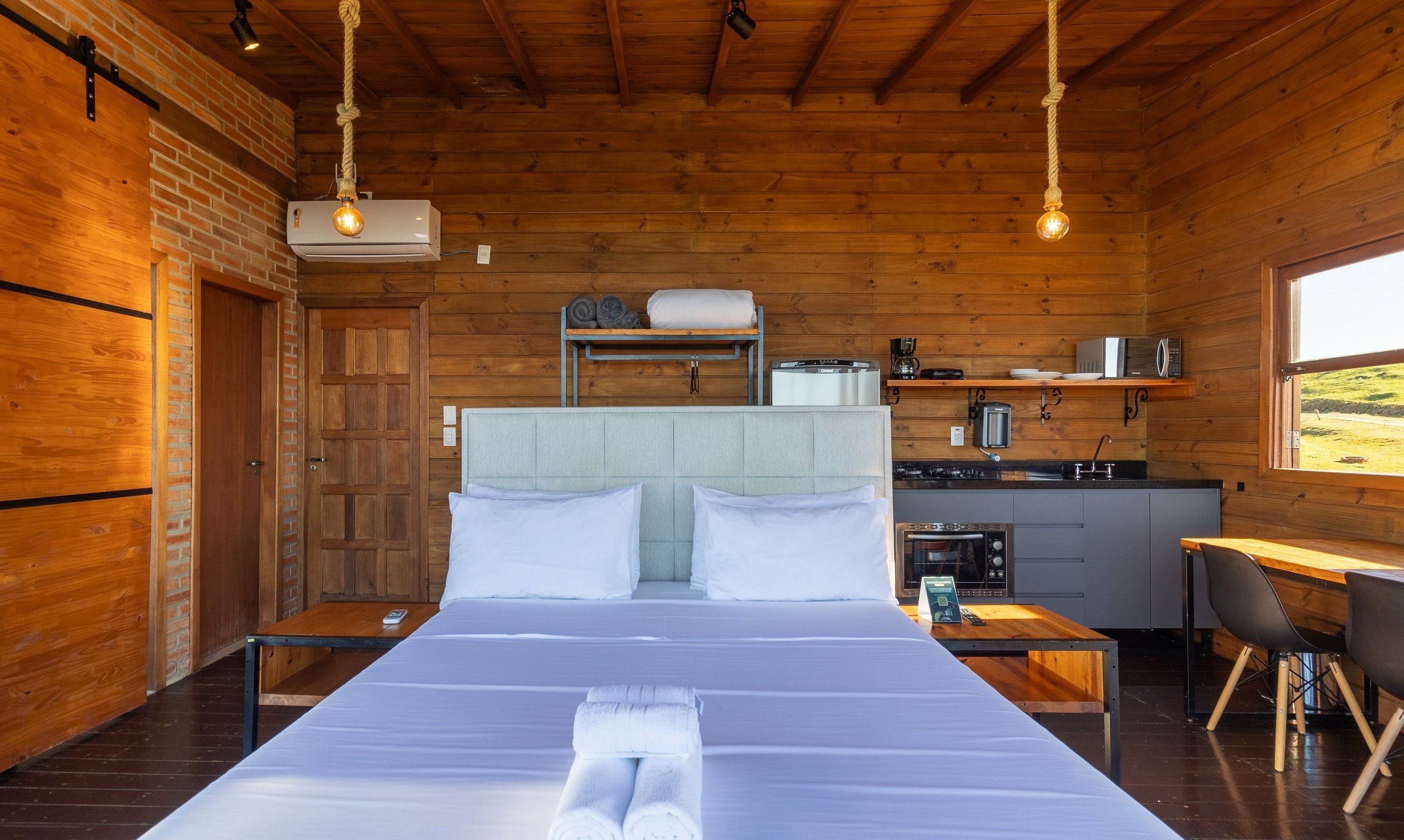 Interior de una cabaña de madera con una cama, kitchenette y comedor.