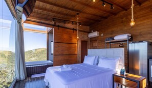 A modern bedroom with a large bed, a wooden ceiling, and a view of the outdoors.