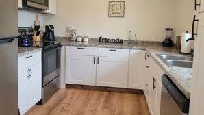 A modern kitchen with white cabinets, a microwave, a kettle, and a coffee maker.