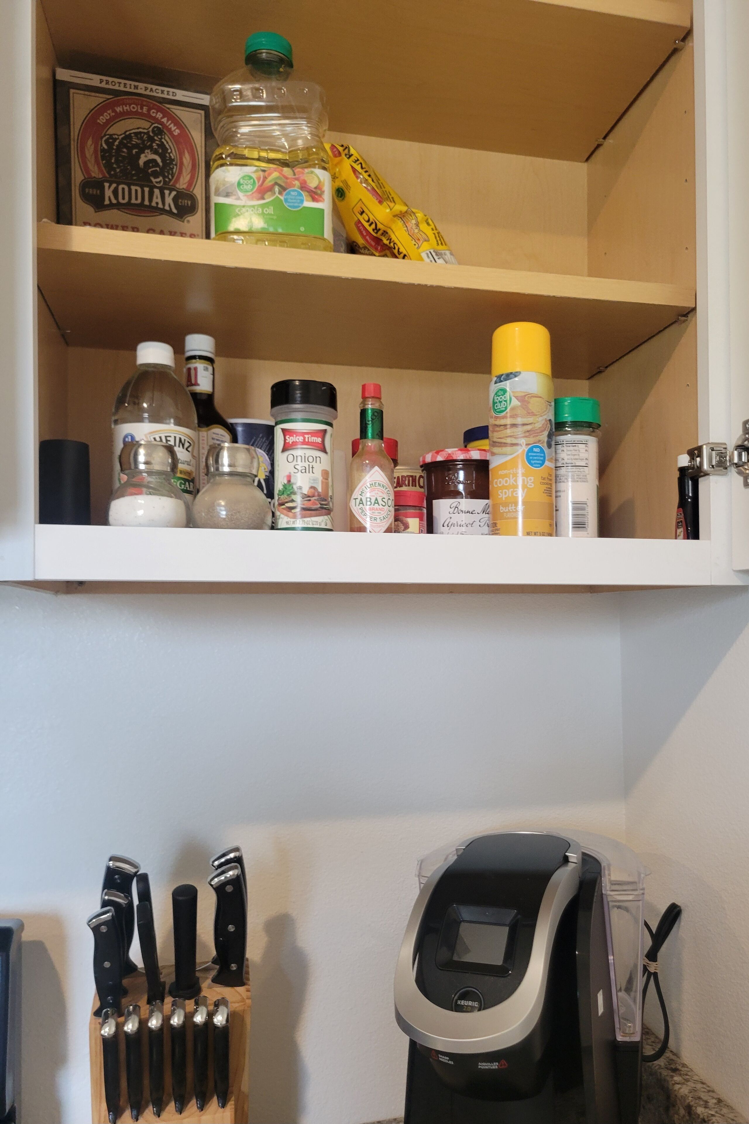 A kitchen shelf with various food items and a knife block.