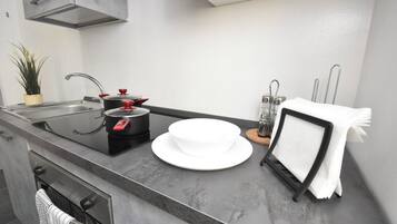 A modern kitchen with a stainless steel sink, black pots, a white bowl, and a towel rack.