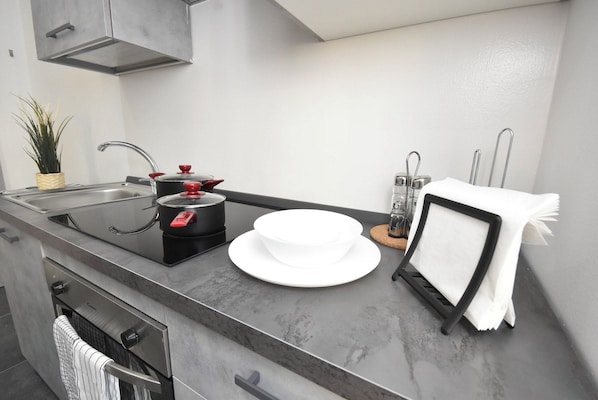 A modern kitchen with a stainless steel sink, black pots, a white bowl, and a towel rack.