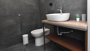 A modern bathroom with a white sink, a round mirror, and a bidet. - Crisvan Residence Igea Marina (Bellaria-Igea Marina)