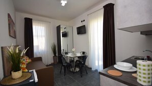 Ein modernes Wohnzimmer mit einer Couch, einem Esstisch, Stühlen und einer Küchenzeile mit Spüle und Arbeitsplatte.