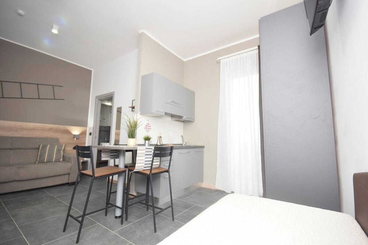 A modern, compact living space with a kitchenette, a dining area, and a large bed.