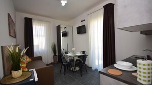 A modern living room with a sofa, dining table, chairs, and a kitchen area with a sink and counter. - Crisvan Residence Igea Marina (Bellaria-Igea Marina)
