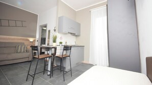 Ein modernes, kompaktes Wohnzimmer mit Küchenzeile, einem Essbereich und einem großen Bett.