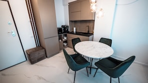 A compact kitchen with a dining area, including a marble table and dark chairs. - Wave 4 Apartments (Navodari)