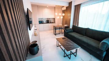 A modern living room with a sofa, a coffee table, and a dining area with chairs.