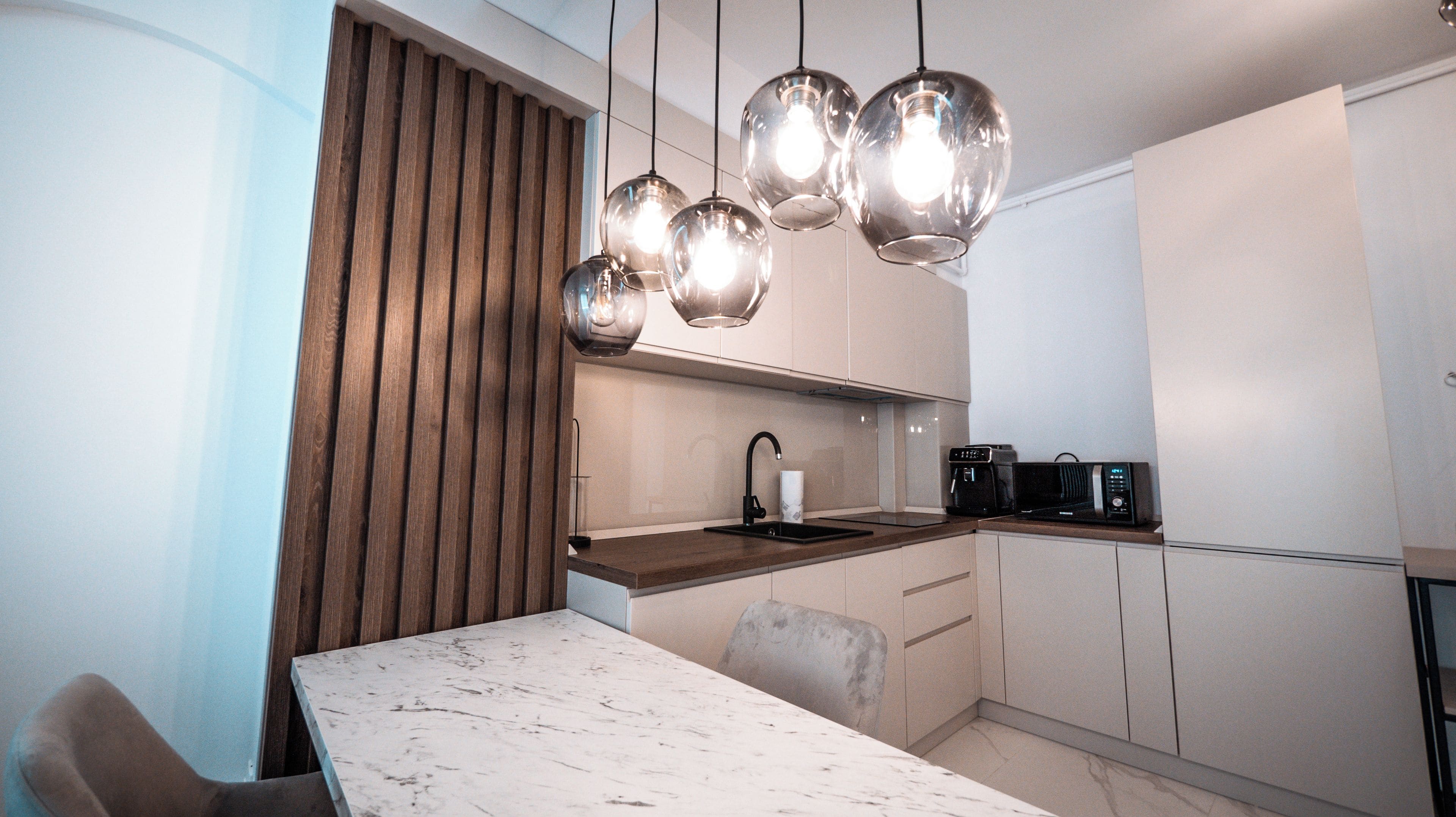 Una cocina moderna con encimera de mármol, pared de listones de madera y una mesa de comedor.