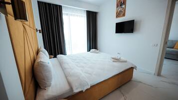Een hotelkamer met een bed, een flatscreen televisie aan de muur en een raam met gordijnen.